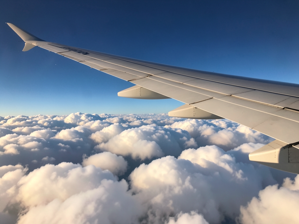Airplane wing above bright clouds morning light clear