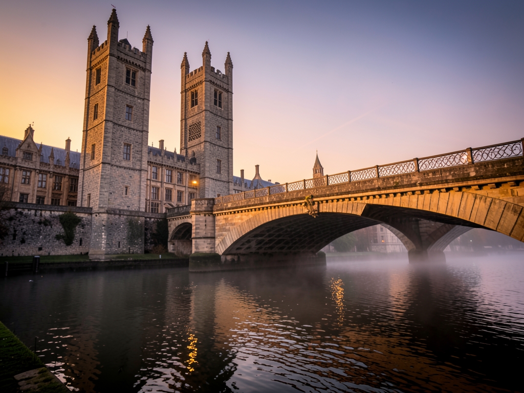 London riverside with historic stone towers arched bridge