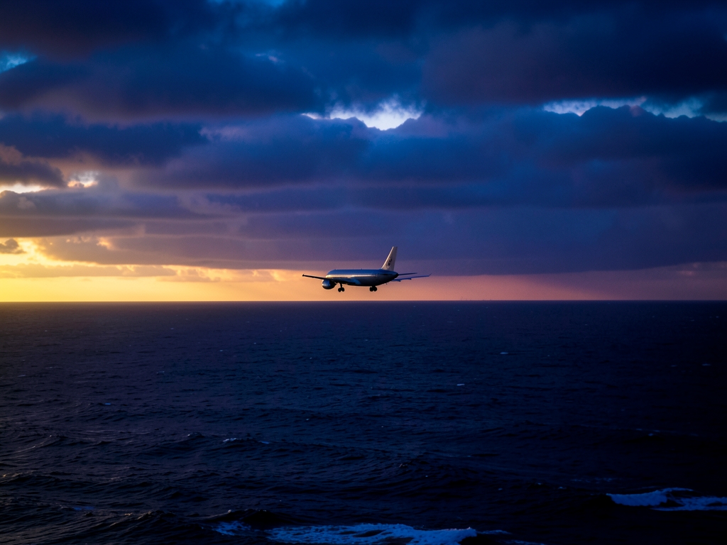 lone commercial aircraft gliding over dark Pacific Ocean