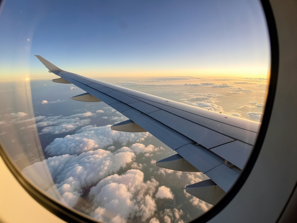 Airplane wing above layered clouds sunset silver metal