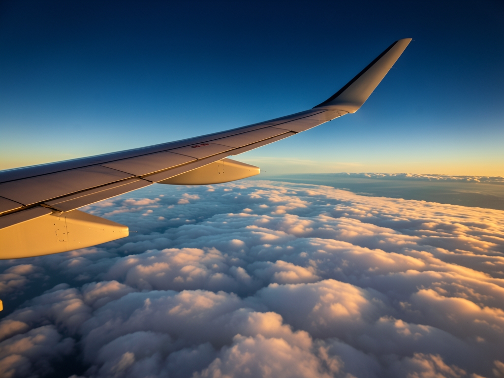 Airplane wing above silver cloud layer golden hour