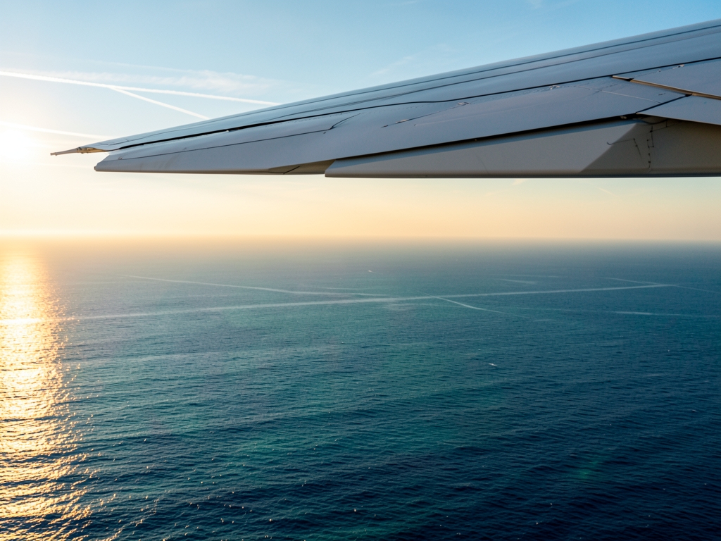 Airplane wing above Atlantic clouds golden hour endless