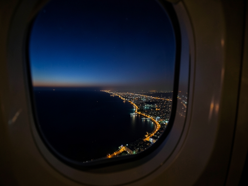 nighttime view over coastal city from plane window