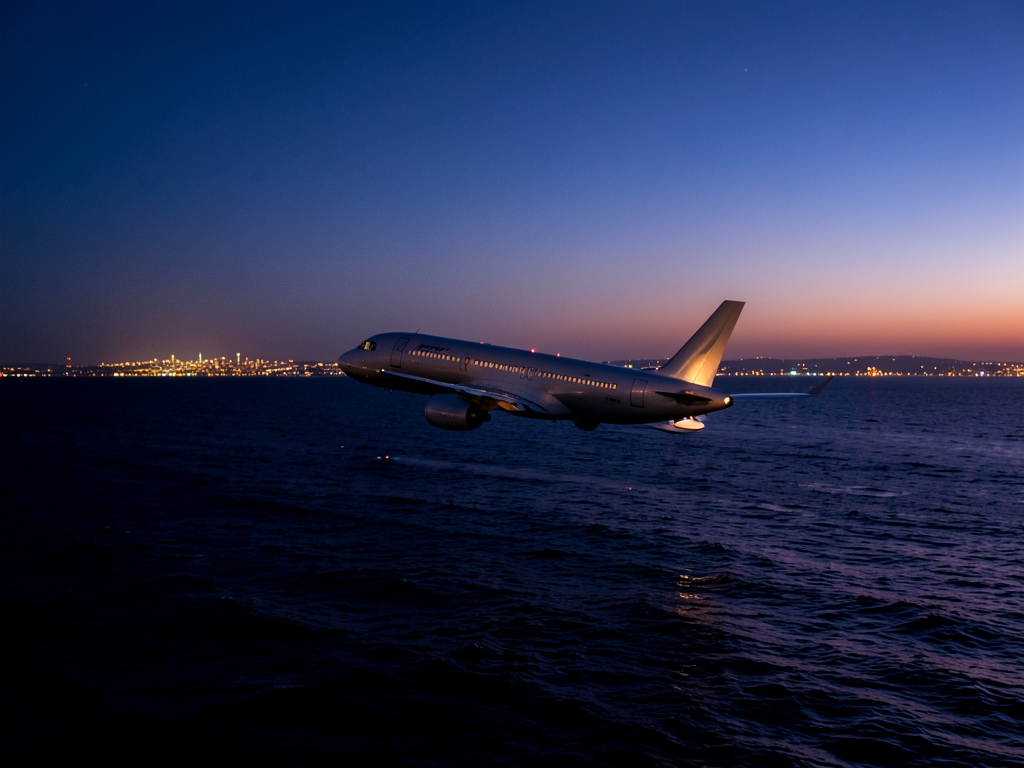 commercial glides over dark waters Atlantic twilight silhouette