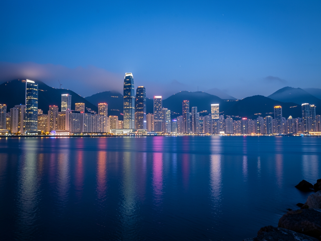 Hong Kong harbor dusk with glowing towers calm