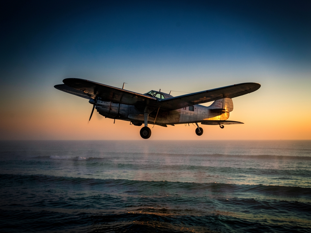 vintage airplane glides over misty Atlantic Ocean dusk