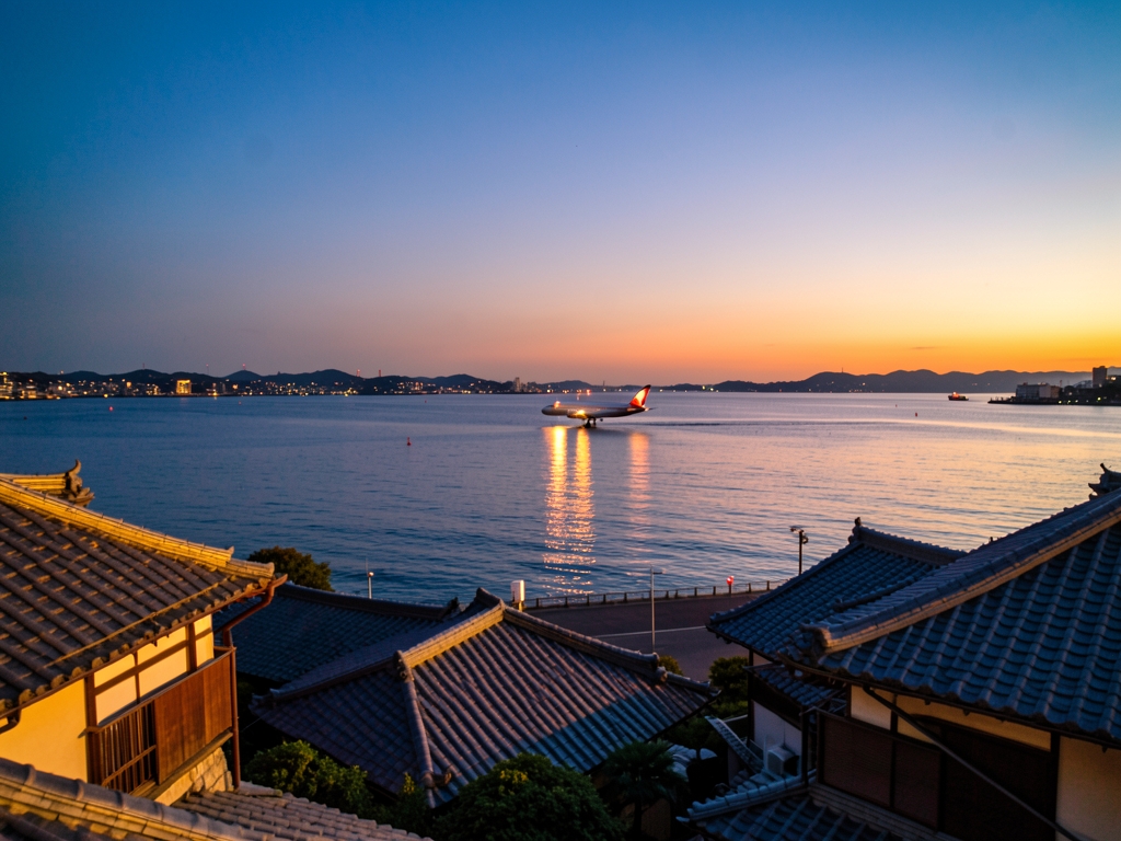 Serene Tokyo coastline dusk with descending airliner over