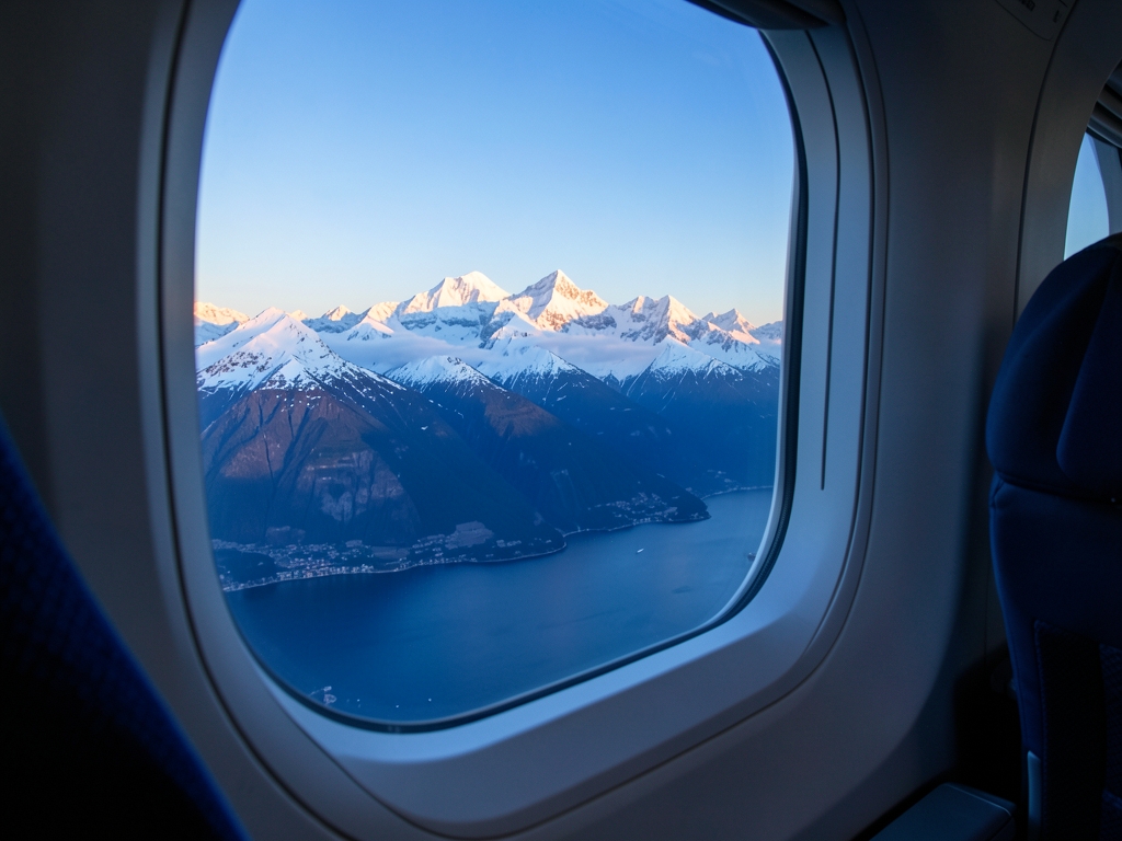 Airplane cabin window view over snow capped Alps Adriatic