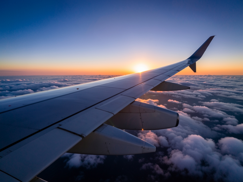 Wide airplane wing over vast Atlantic cloud layer