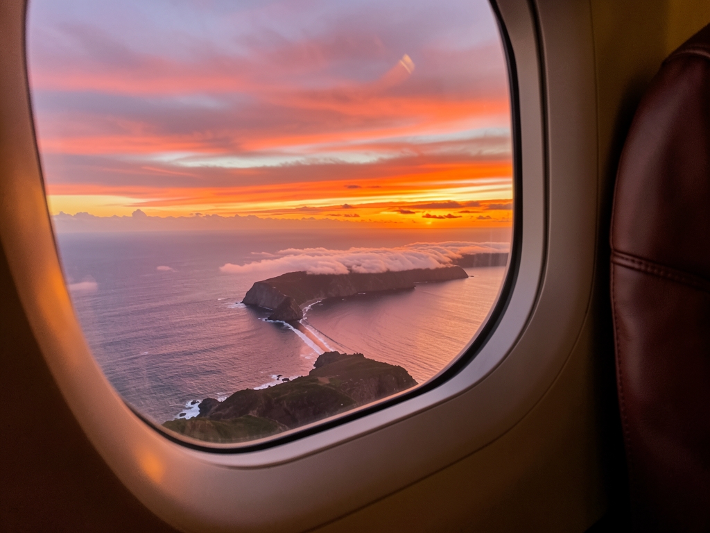 Sunset over Pacific coastline seen through airplane window